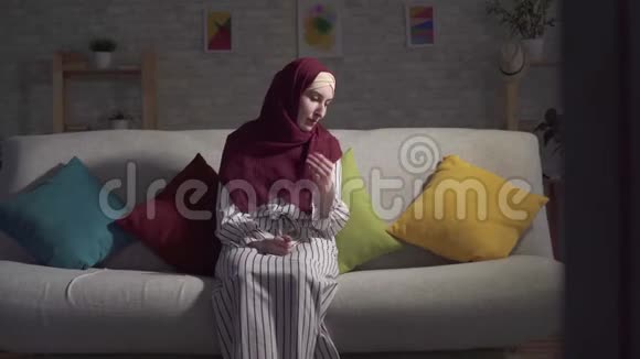 沮丧的年轻穆斯林妇女坐在客厅的沙发上哭泣视频的预览图