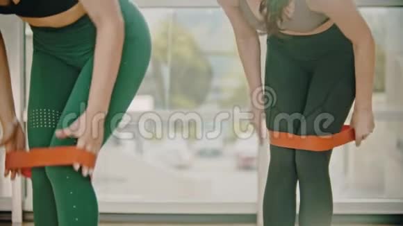 两名女子在健身室接受绿腿训练在大腿之间系一条伸展带视频的预览图
