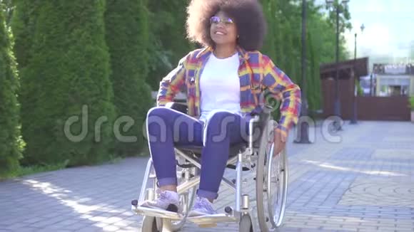 一位微笑的年轻非裔美国妇女在街上轮椅上残疾的肖像视频的预览图