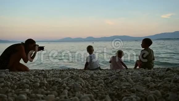 专业摄影师拍摄三个孩子在海里扔石子的照片视频的预览图