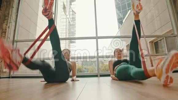 两个健康的女人用脚踝之间的拉伸带训练腿视频的预览图