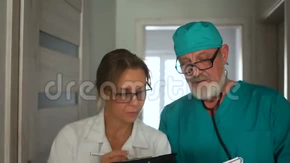 医生正在和一位白发苍苍的成熟男医生谈话走在诊所的走廊上视频的预览图