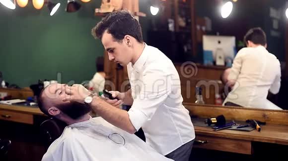 刮胡子刮胡子年轻的理发师集中行动工作场所背景上的镜子反射侧视图视频的预览图