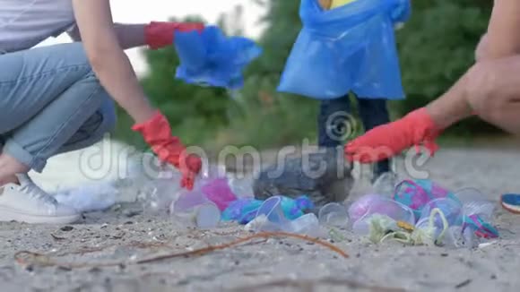 带着戴着橡胶手套的小孩的年轻家庭在打扫卫生的同时从肮脏的沙滩上收集垃圾视频的预览图