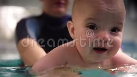 母亲或游泳教练穿着特殊的游泳服装把孩子抱在水面上带领他穿过水面视频的预览图