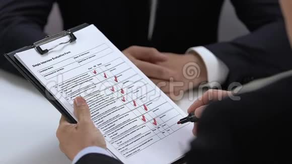 男性雇主与申请人握手填写面试评价表视频的预览图
