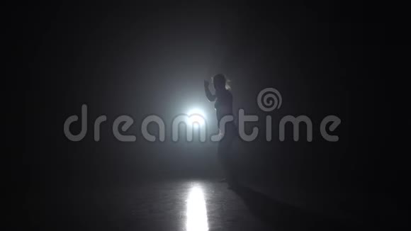 女士在黑暗中练习卡波伊拉与聚光灯在演播室慢动作视频的预览图