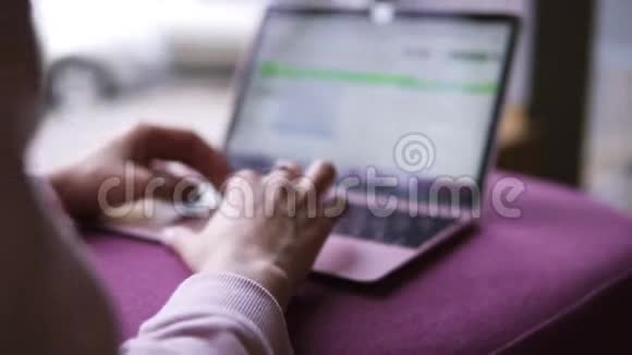 在公共咖啡馆里躺在沙发上的时候穿着粉红色毛衣的年轻女孩放松了打字浏览视频的预览图