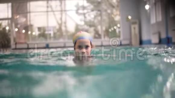 微笑的小女孩没有泳镜在游泳池里水下游泳少女在水下潜水以上及以上的相片视频的预览图