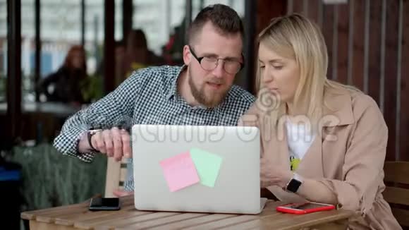 年轻的配偶们在露天露台的咖啡馆里笔记本电脑屏幕讨论着视频的预览图