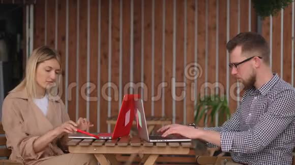 街边咖啡馆的两名男女访客正在使用笔记本电脑视频的预览图