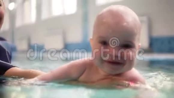 妈妈或教练教小男孩在室内游泳池游泳把他抱在水下快乐的孩子享受视频的预览图