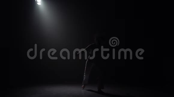 漂亮的女人在黑暗中练习卡波伊拉对抗演播室的聚光灯视频的预览图