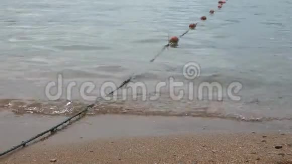 小浪在沙滩上冲浪有漂浮物的长绳进入水中视频的预览图