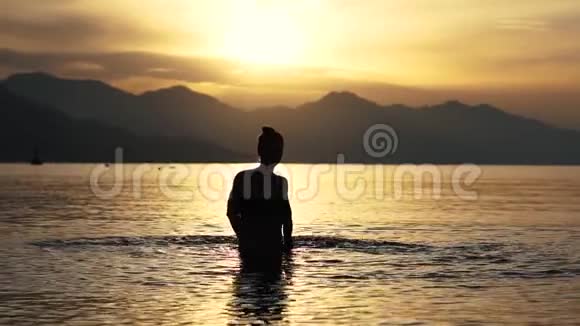 日出时一个在海里缓慢地溅水的女孩的小公主视频的预览图