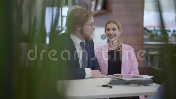 在现代车展上优雅的男女穿着正式西装坐在桌子旁买新车女售货员给钥匙视频的预览图