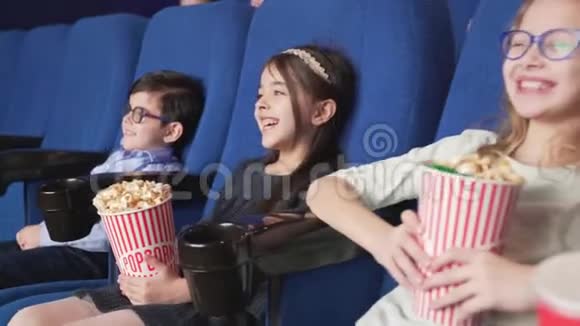 一群微笑的孩子坐在电影院舒适的椅子上视频的预览图