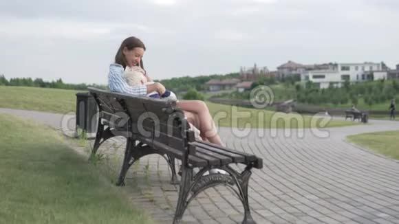 妈妈和儿子坐在公园的长凳上等待日落视频的预览图