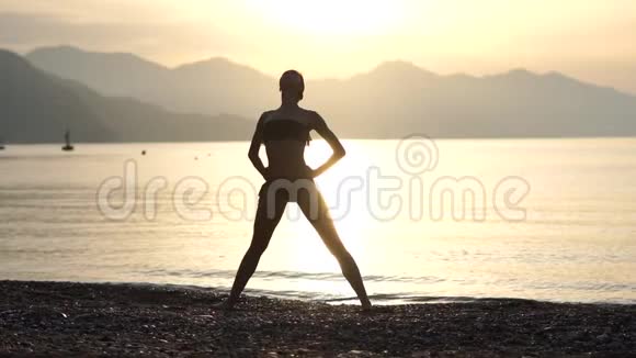 早晨日出时一个女孩在海边慢动作练习瑜伽视频的预览图