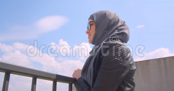 年轻漂亮的穆斯林女商人戴着头巾戴着眼镜看着城市景色转向视频的预览图