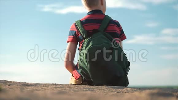 在日落时分穿着一件背着背包的红色t恤坐在高高的山上享受着自然和自由视频的预览图