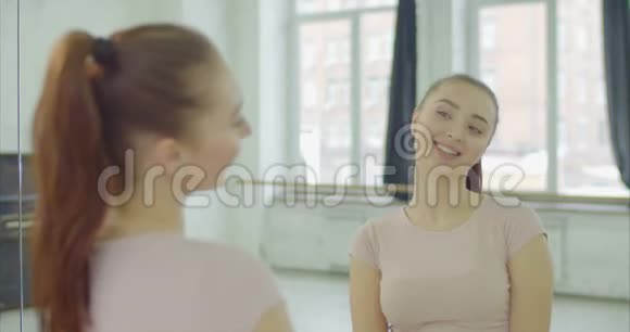 无忧无虑的漂亮女人在室内对着镜子眨眼视频的预览图