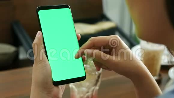 4K女士在咖啡店使用带有空白绿色屏幕模型的移动智能手机使用手指触摸屏幕和幻灯片滑动视频的预览图