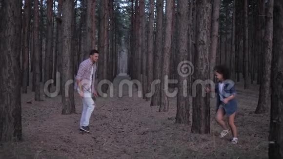 在森林里度过一个愉快的周末年轻的父亲玩得很开心在一排排松树之间慢慢地赶上了小女儿视频的预览图