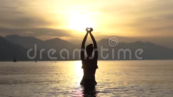 女人的心从她的双手头顶上站在海里慢动作视频的预览图