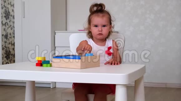 无聊的小女孩2岁玩教育玩具堆叠和安排五颜六色的数字通过学习视频的预览图