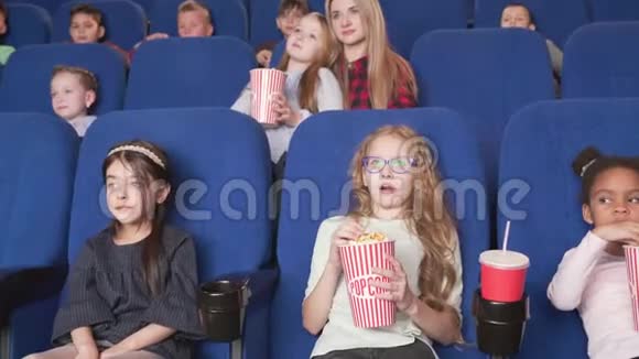 可爱的女孩和另一个快乐的孩子在电影院看卡通视频的预览图