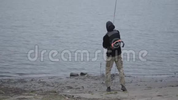 清晨年轻自信的渔夫穿着卡其布裤在城市附近的河流里钓鱼视频的预览图