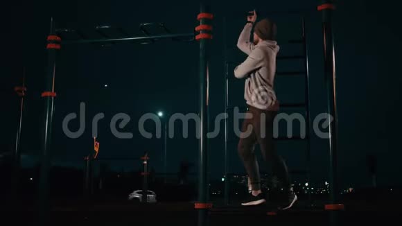 在户外活动的人在夜间把腿吊在水平杆上视频的预览图