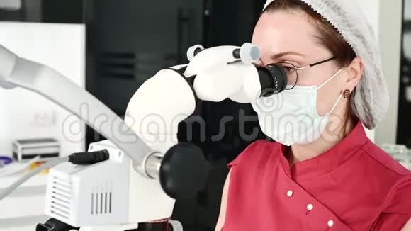 一名戴眼镜的妇女带着一名专业牙医在她的口腔显微镜下工作视频的预览图