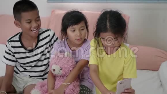 年轻的亚洲儿童在卧室用智能手机摸索自拍视频的预览图