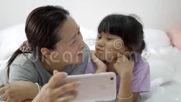 快乐亚洲家庭自拍与智能手机在卧室视频的预览图