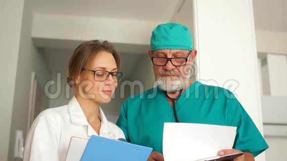 近距离画像两个医生一个成熟的男人和一个年轻的女人医生看着框架微笑医务所职员视频的预览图
