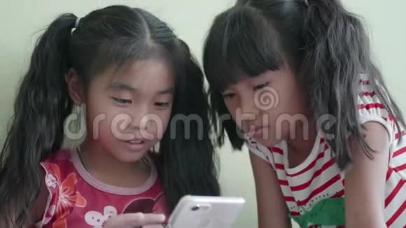 孩子们小女孩在家里使用智能手机视频的预览图