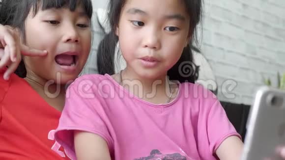 年轻的亚洲儿童女孩在客厅用智能手机自拍视频的预览图