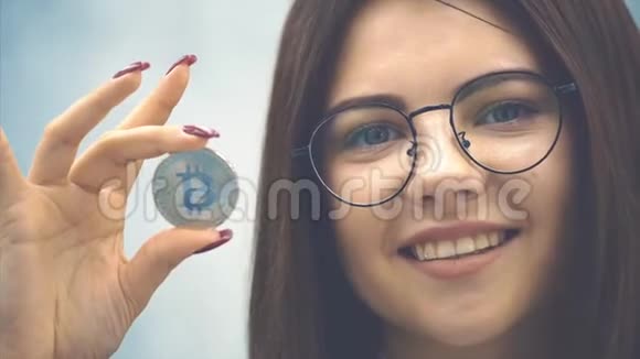 微笑的年轻女商人穿着正式的黑色西装露出一枚银币把注意力集中在硬币上视频的预览图