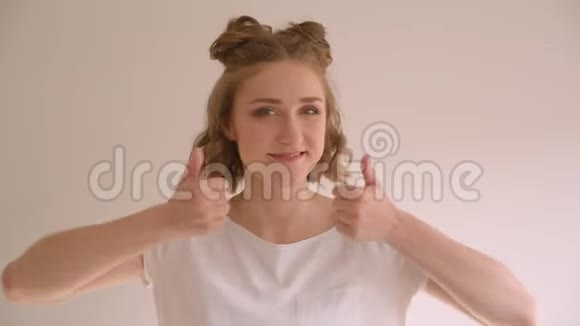 年轻可爱的白种人女性特写镜头她的发髻上竖起大拇指开心地笑着看着镜头视频的预览图