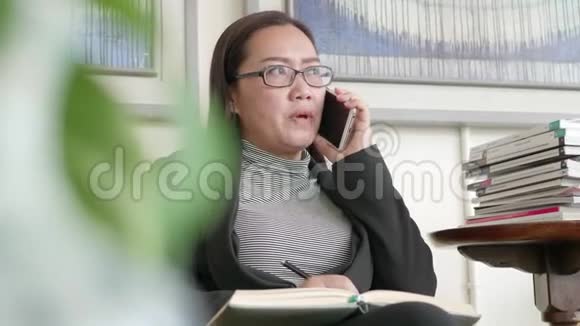 女人在家庭办公室用智能手机写笔记视频的预览图