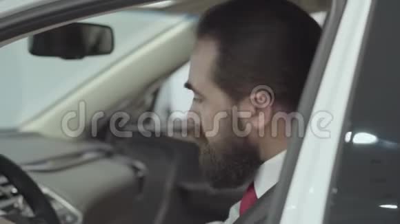 肖像画吸引人可爱自信留胡子的商人坐在车里检查从新买的汽车视频的预览图