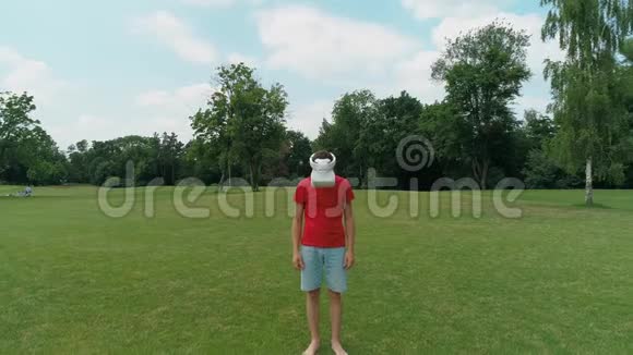 带着VR耳机的人的空中视野他抬起头仰望公园里的摄像机视频的预览图