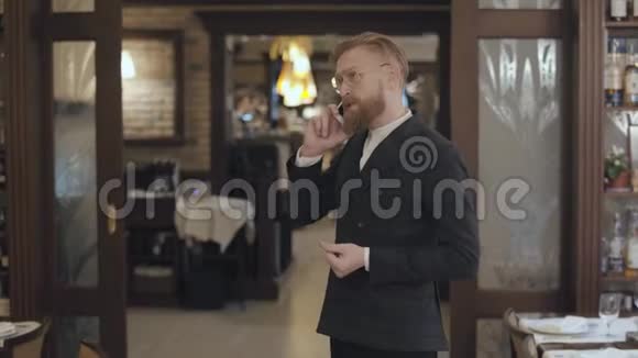一位戴着时髦眼镜留着红胡子的成功商人在一家昂贵餐馆的牢房里谈话的画像视频的预览图