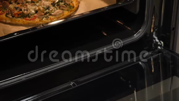女人在家里从烤箱里拿热烤披萨在厨房做披萨把吃完的披萨从电烤箱里拿出来视频的预览图