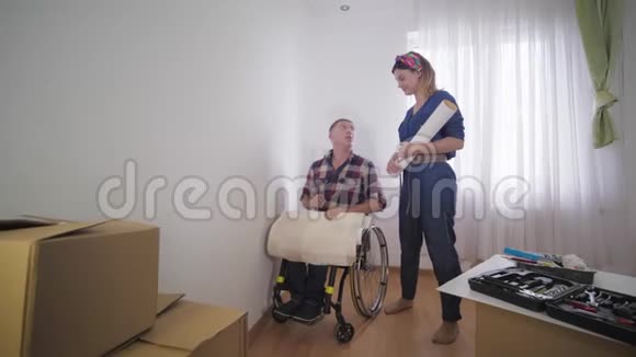 轮椅残疾人爱心人士选择年轻漂亮的妻子在维修期间换新墙纸视频的预览图