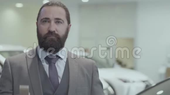 一个成功留胡子的商人穿着商务服的肖像展示了一辆豪华轿车的钥匙看着镜头视频的预览图