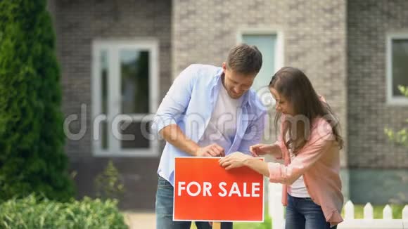 有吸引力的夫妇拥抱在房子前面安装销售招牌生活视频的预览图
