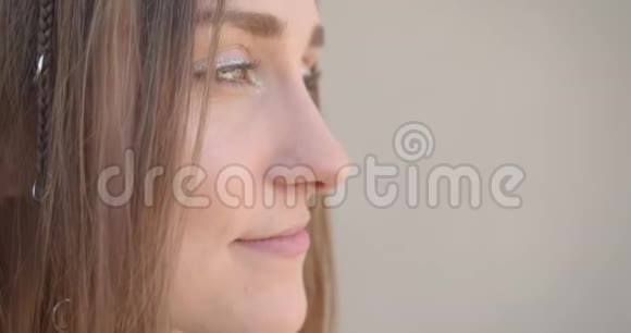 特写侧景拍摄年轻漂亮的白种人女性脸有发环和闪光的化妆眼睛快乐视频的预览图